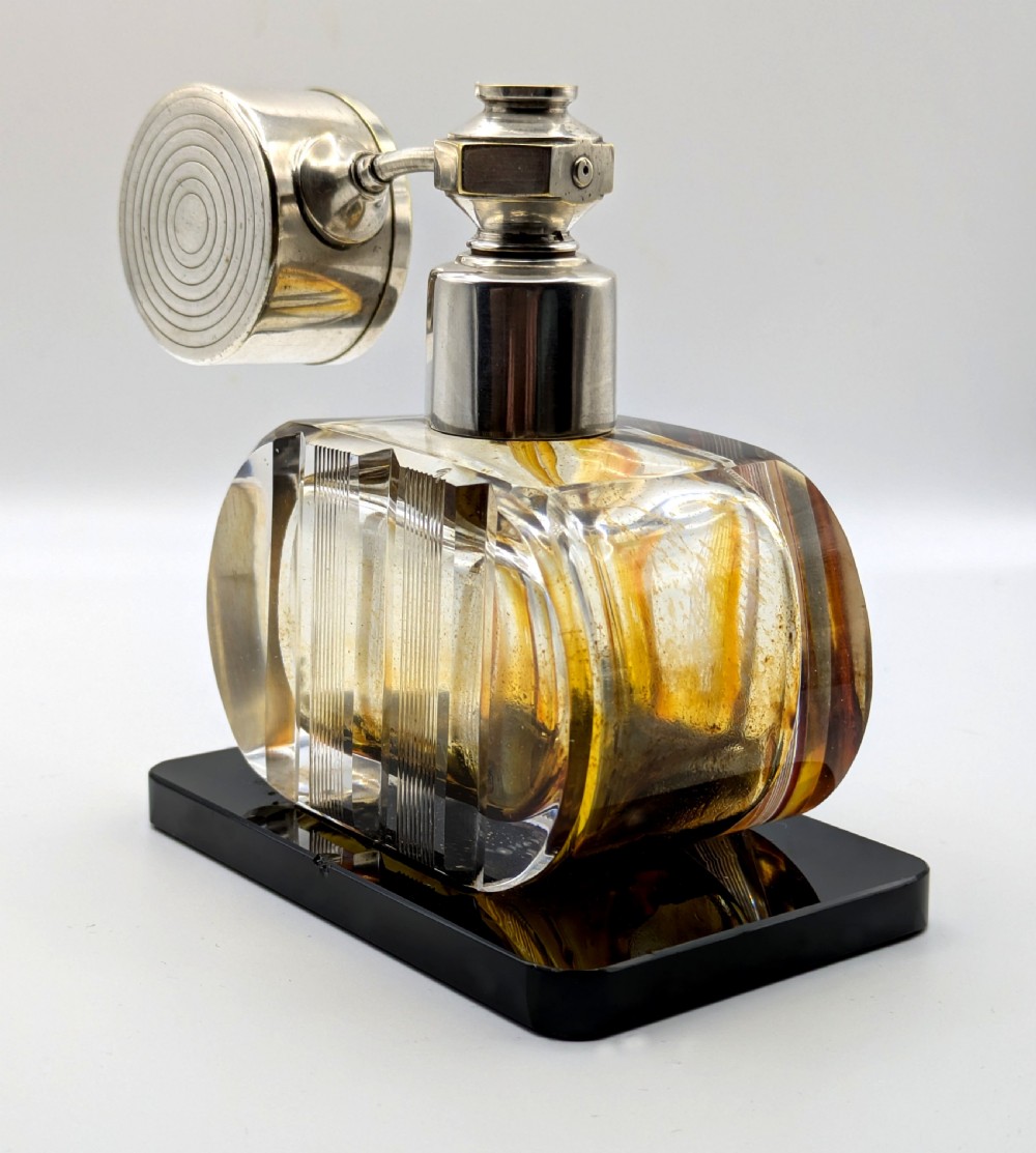 A French Art Deco cut glass perfume atomiser featuring a silver-toned metal spray mechanism mounted on a flat black rectangular base. View VII