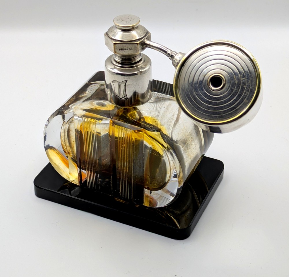 A French Art Deco cut glass perfume atomiser featuring a silver-toned metal spray mechanism mounted on a flat black rectangular base. View IX
