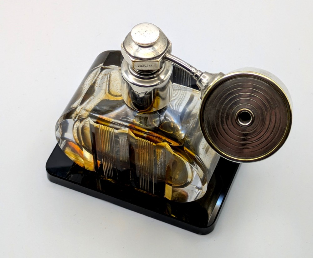 A French Art Deco cut glass perfume atomiser featuring a silver-toned metal spray mechanism mounted on a flat black rectangular base. View X