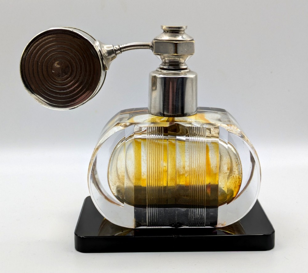 A French Art Deco cut glass perfume atomiser featuring a silver-toned metal spray mechanism mounted on a flat black rectangular base. View XII