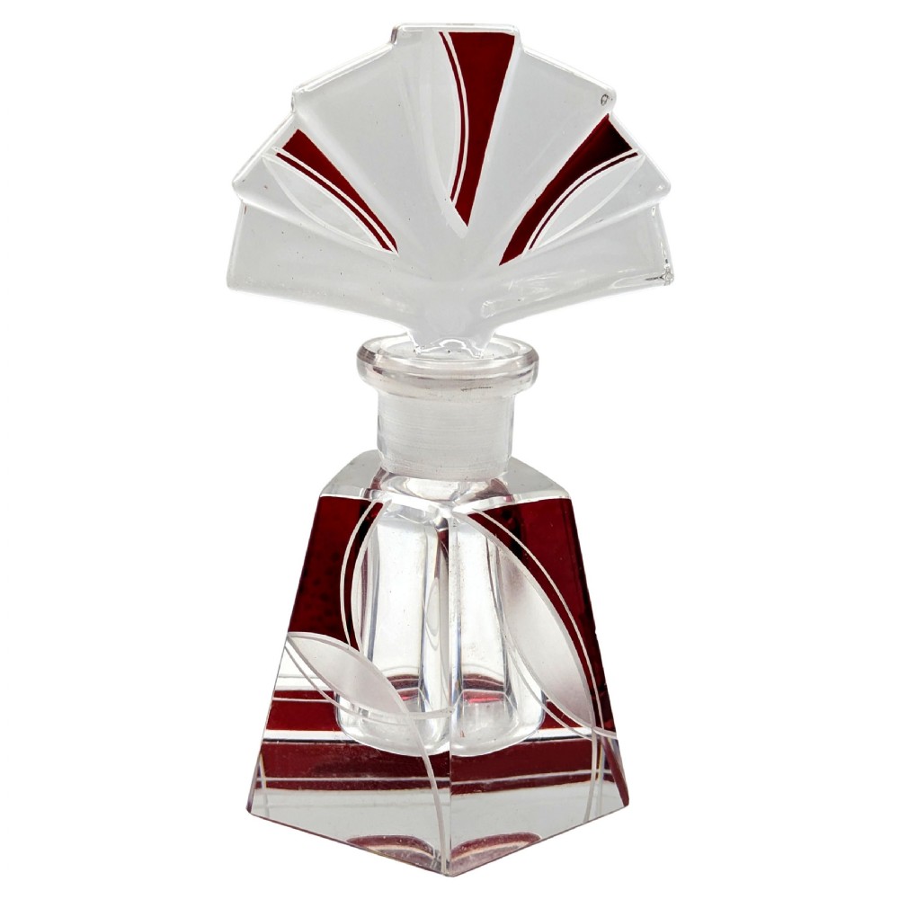 An Art Deco clear glass perfume bottle with red geometric accents and a large fan-shaped stopper.
