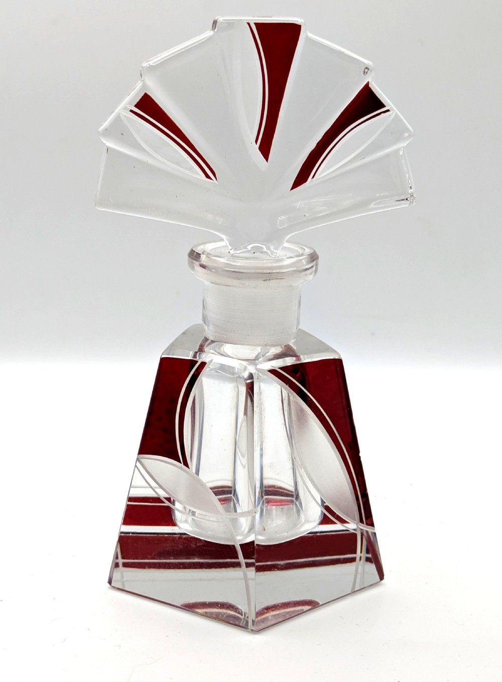 An Art Deco clear glass perfume bottle with red geometric accents and a large fan-shaped stopper. View II