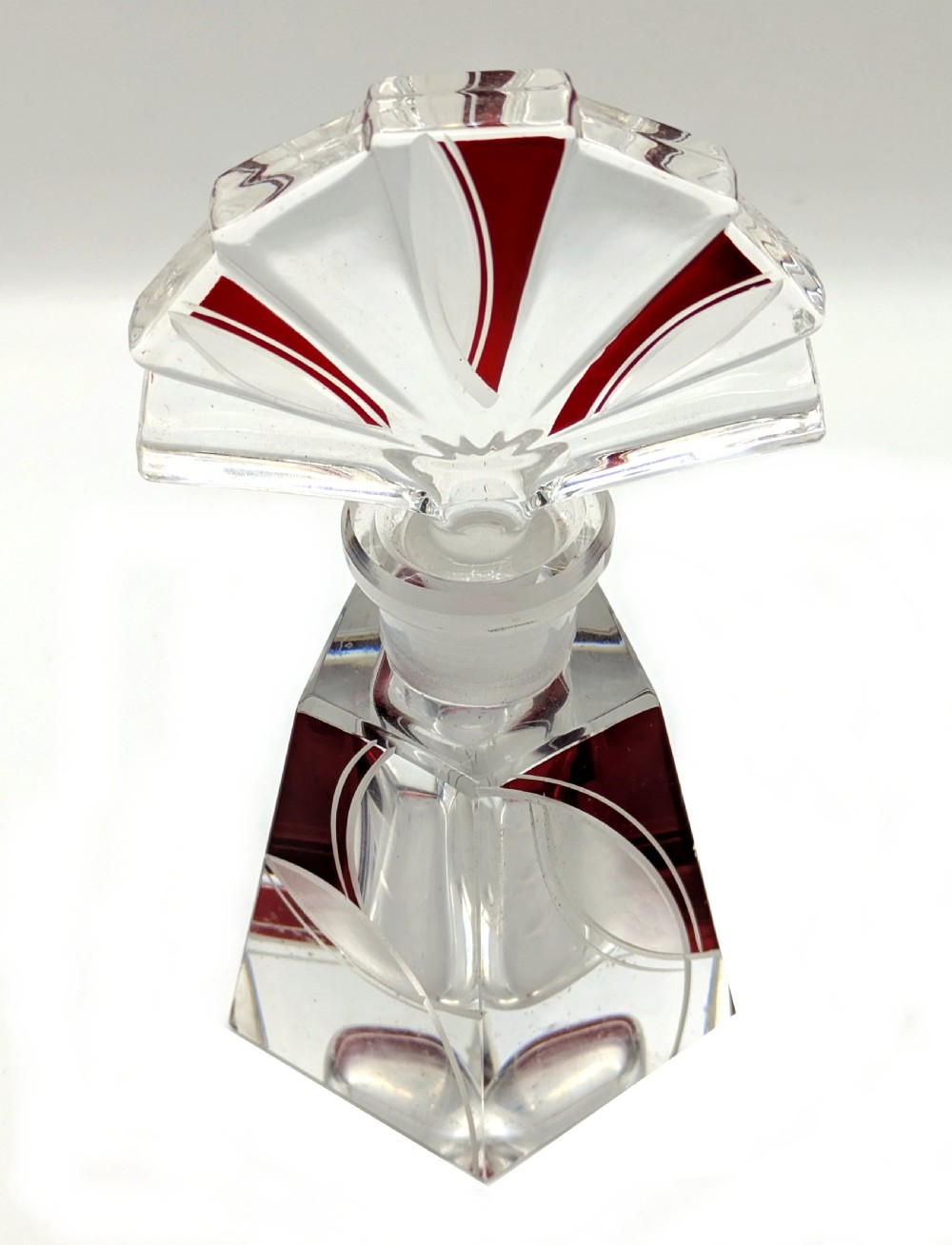 An Art Deco clear glass perfume bottle with red geometric accents and a large fan-shaped stopper. View III