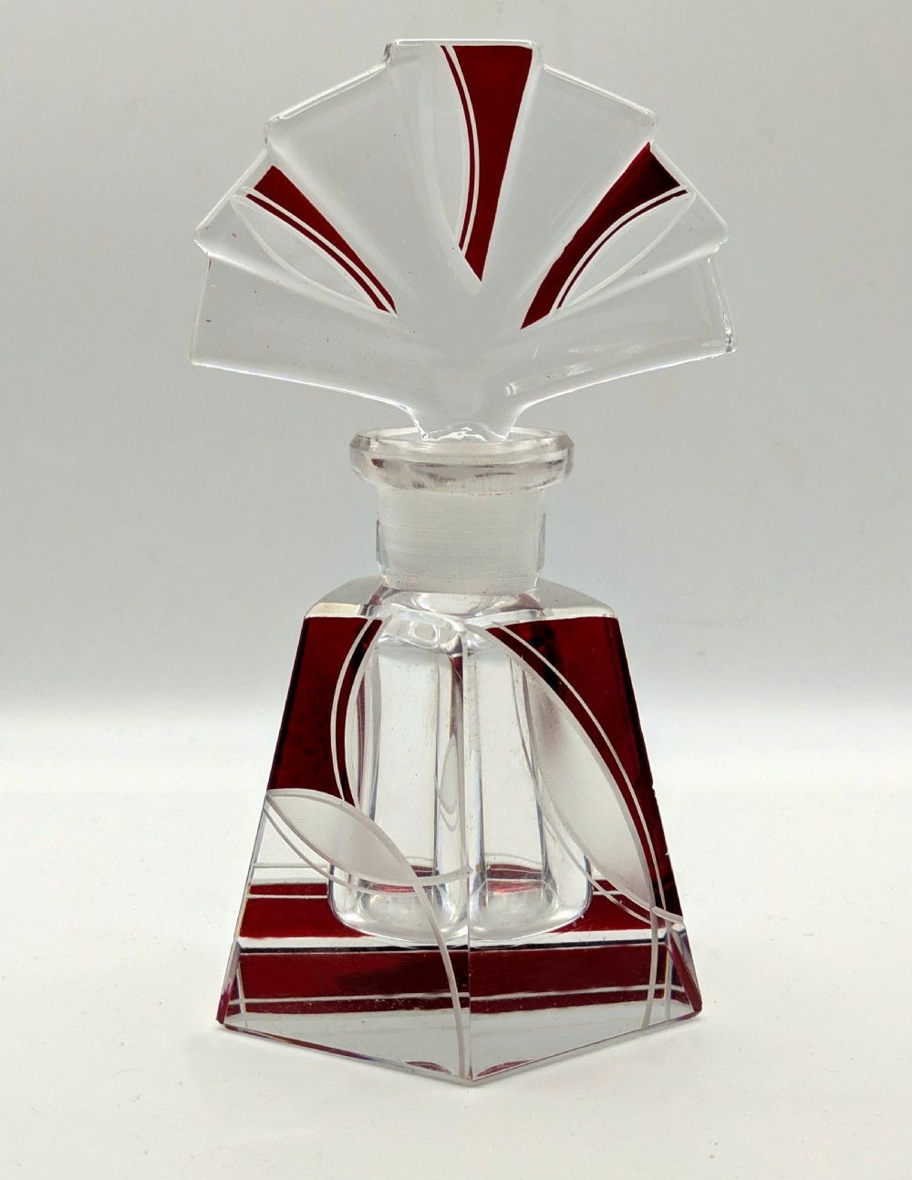 An Art Deco clear glass perfume bottle with red geometric accents and a large fan-shaped stopper. View IV