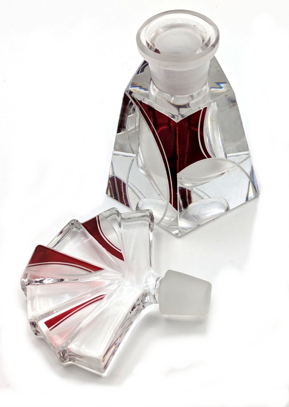 An Art Deco clear glass perfume bottle with red geometric accents and a large fan-shaped stopper. View VII