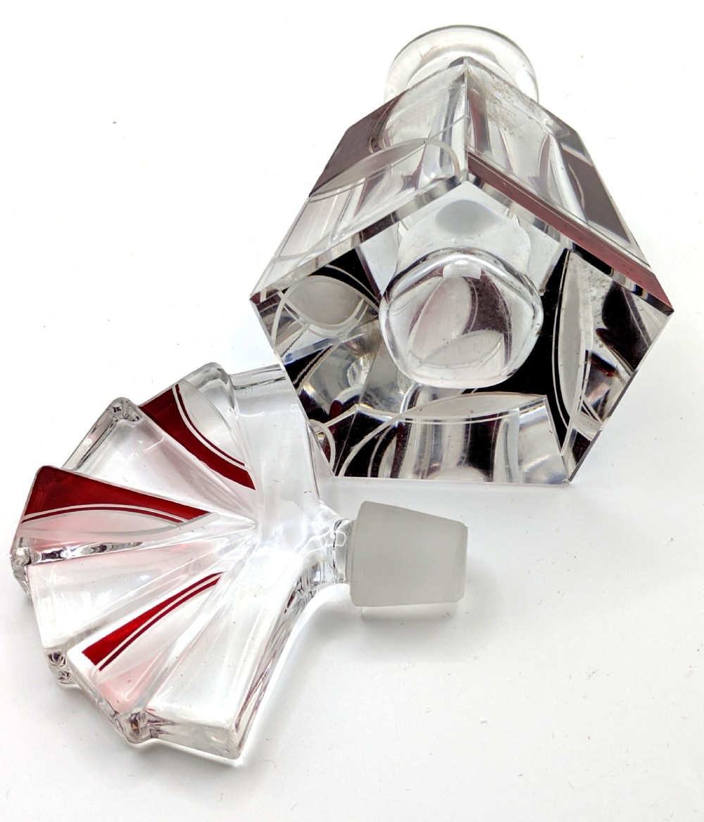 An Art Deco clear glass perfume bottle with red geometric accents and a large fan-shaped stopper. View IX