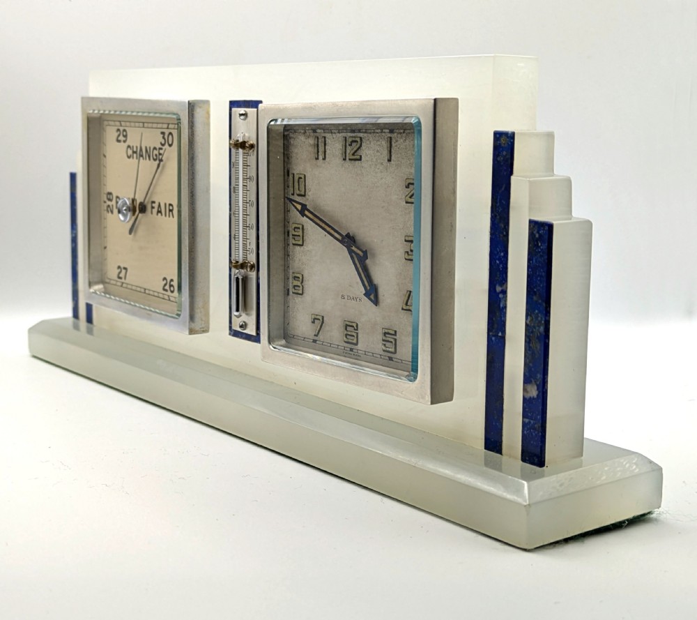 An Art Deco cream onyx desk weather station featuring a square barometer dial, central thermometer, and square clock face flanked by stepped blue lapis lazuli accents. View II