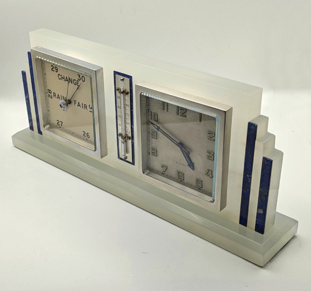 An Art Deco cream onyx desk weather station featuring a square barometer dial, central thermometer, and square clock face flanked by stepped blue lapis lazuli accents. View XII