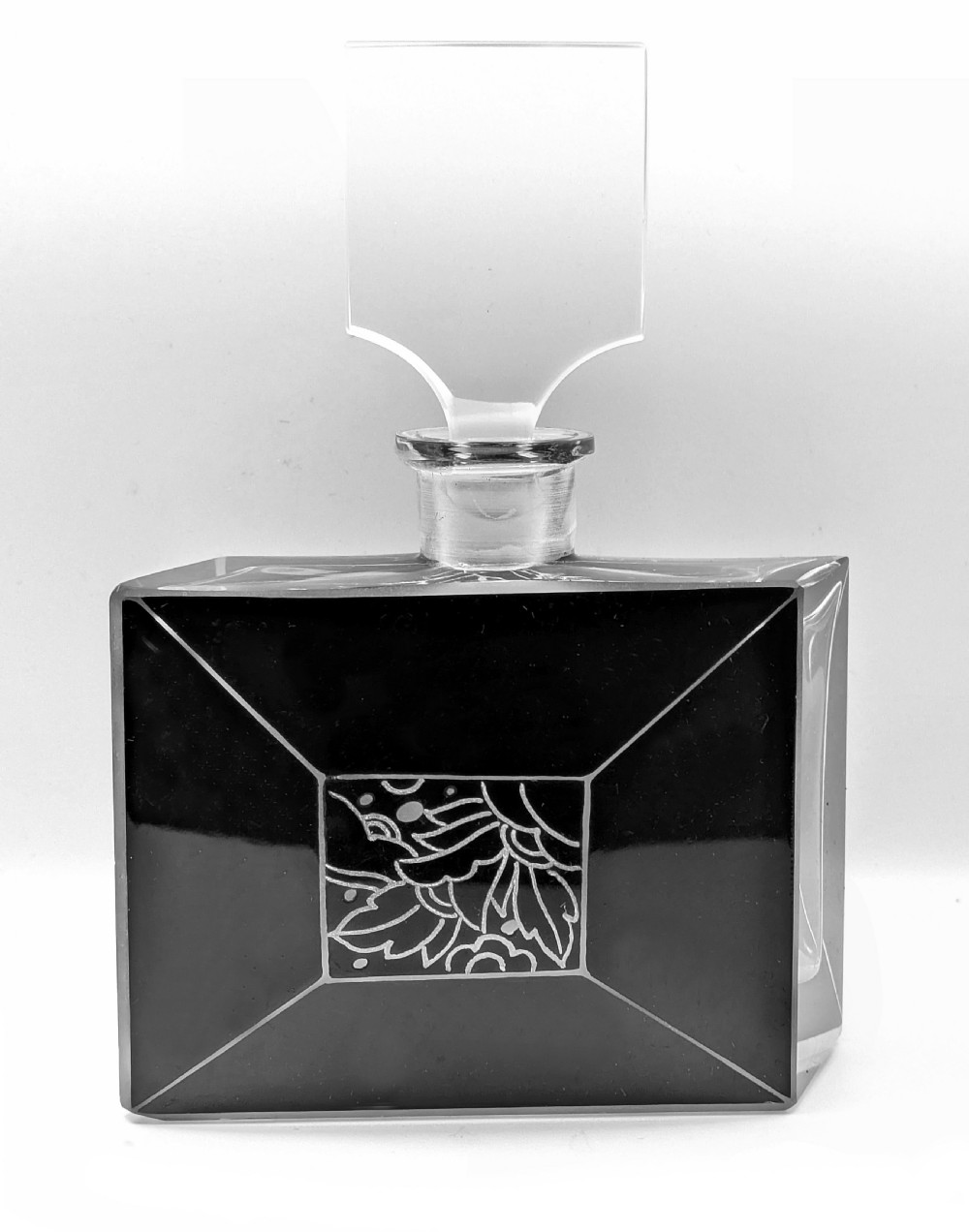 An Art Deco rectangular clear glass perfume bottle featuring black enamelled geometric borders, a central etched floral motif, and a tall rectangular glass stopper. View II