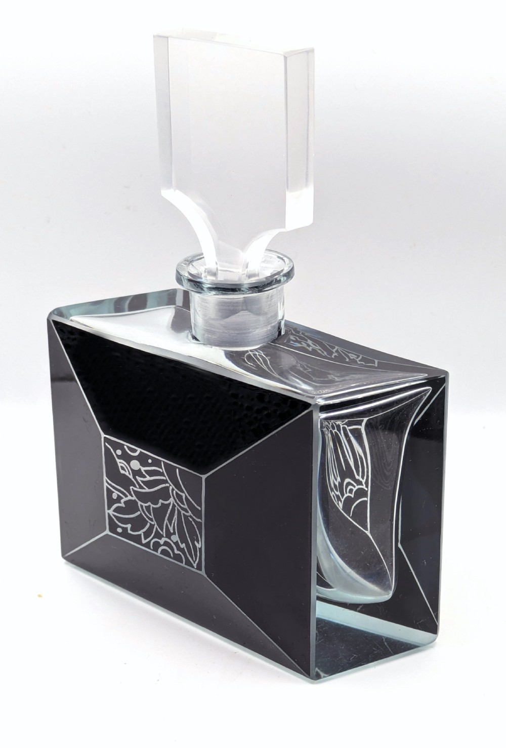 An Art Deco rectangular clear glass perfume bottle featuring black enamelled geometric borders, a central etched floral motif, and a tall rectangular glass stopper. View XI