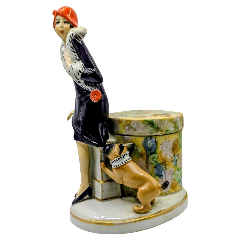 An Art Deco painted porcelain trinket box featuring a flapper lady in a black coat and red cloche hat alongside a small dog. View III
