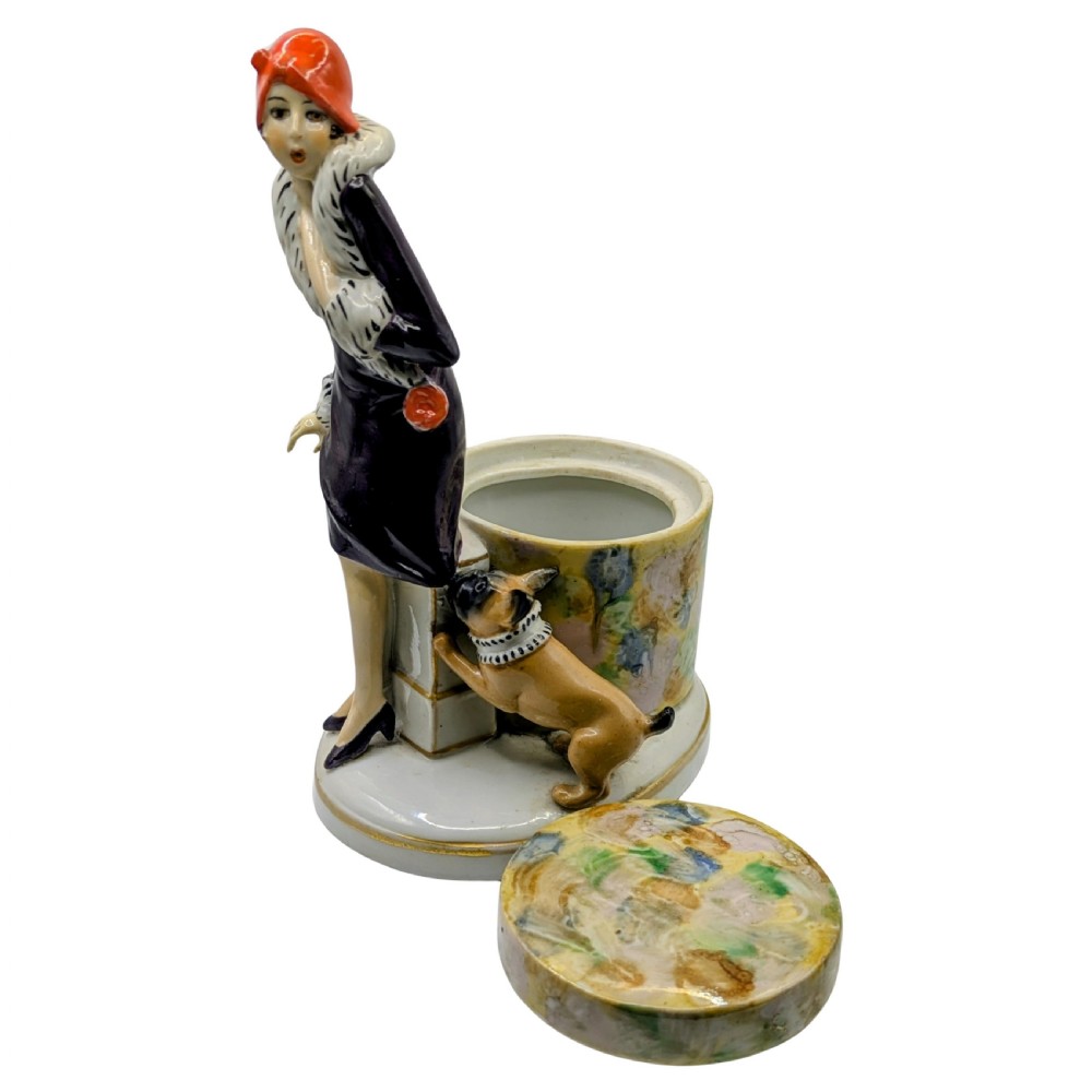 An Art Deco painted porcelain trinket box featuring a flapper lady in a black coat and red cloche hat alongside a small dog. View IV
