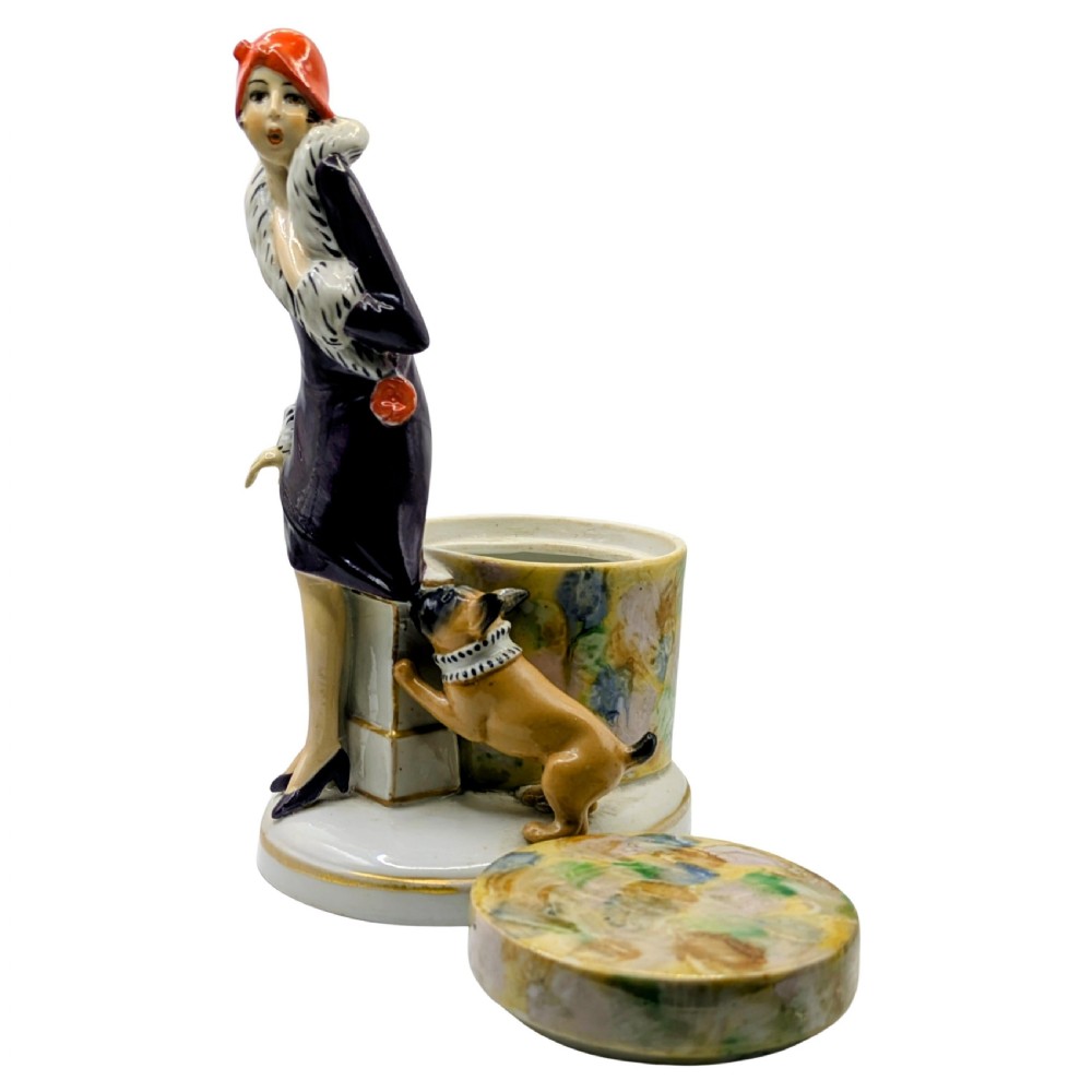 An Art Deco painted porcelain trinket box featuring a flapper lady in a black coat and red cloche hat alongside a small dog. View V