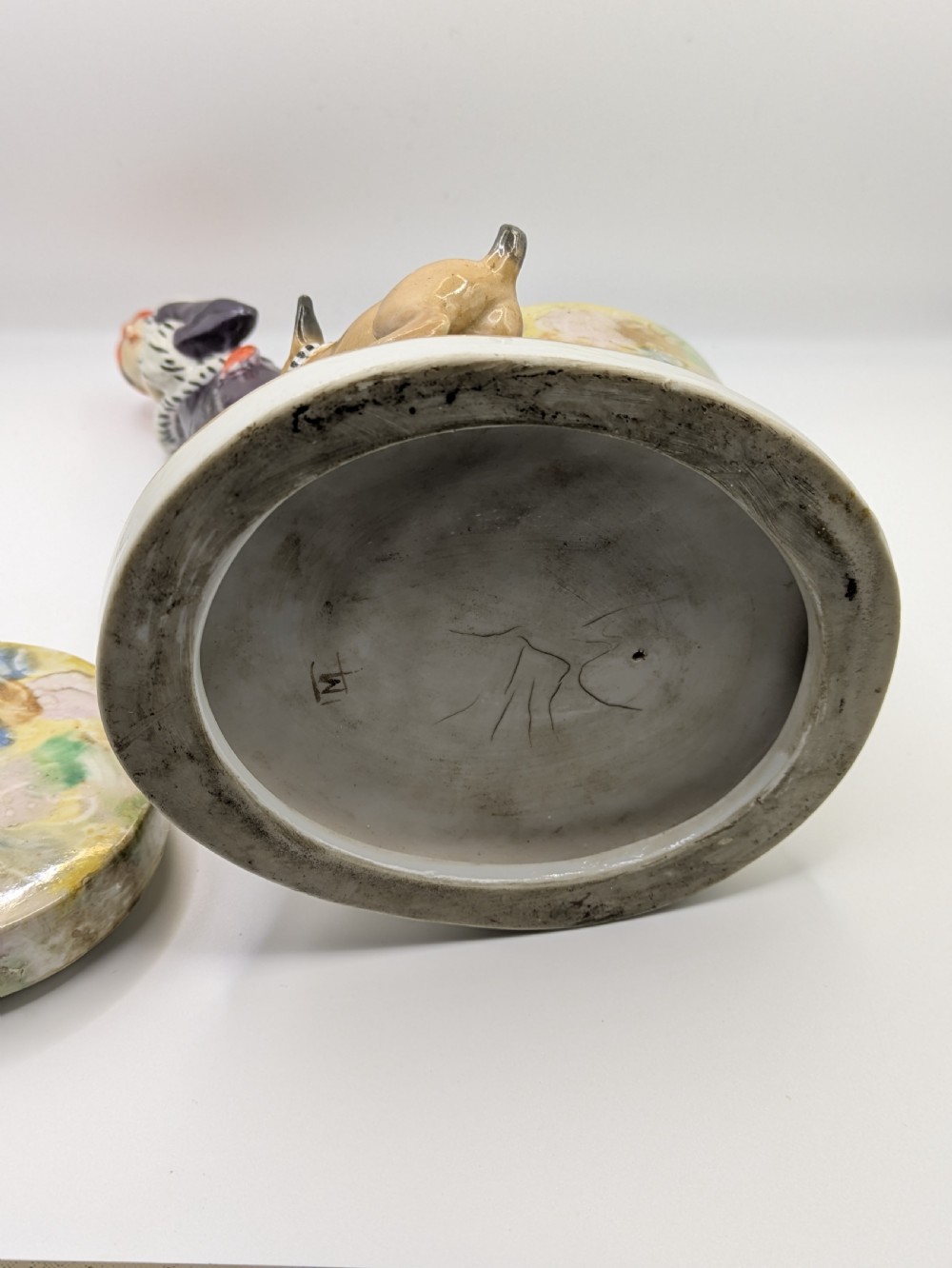 An Art Deco painted porcelain trinket box featuring a flapper lady in a black coat and red cloche hat alongside a small dog. View VI