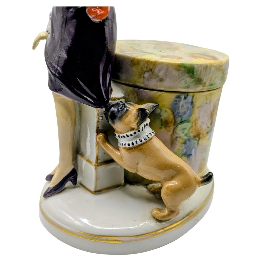An Art Deco painted porcelain trinket box featuring a flapper lady in a black coat and red cloche hat alongside a small dog. View VII