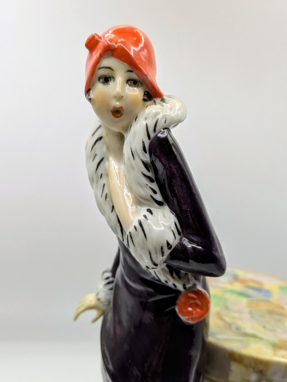 An Art Deco painted porcelain trinket box featuring a flapper lady in a black coat and red cloche hat alongside a small dog. View XII