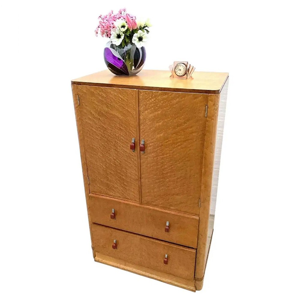 An Art Deco tallboy cabinet crafted from light blonde birds eye maple featuring two upper cupboard doors and two lower drawers.