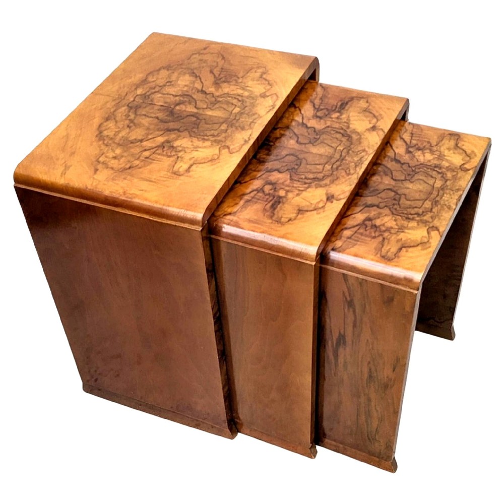 A set of three Art Deco nesting tables crafted from figured burr walnut with smooth curved edges and solid side supports.