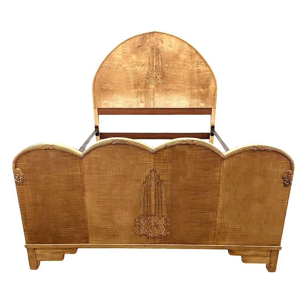 An Art Deco satinwood double bed featuring an arched headboard and a triple-scalloped footboard decorated with central carved fountain motifs.