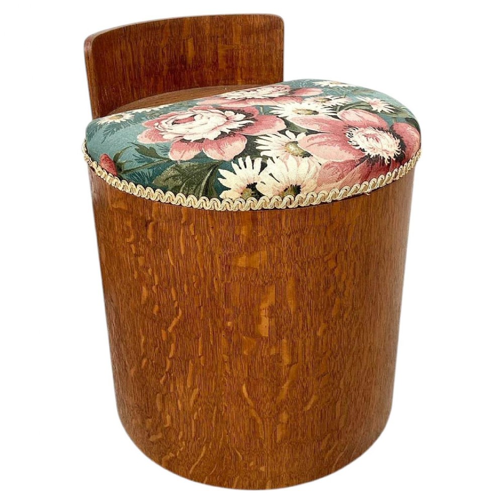 A cylindrical Art Deco oak dressing stool featuring a low wooden backrest and a floral upholstered padded seat.