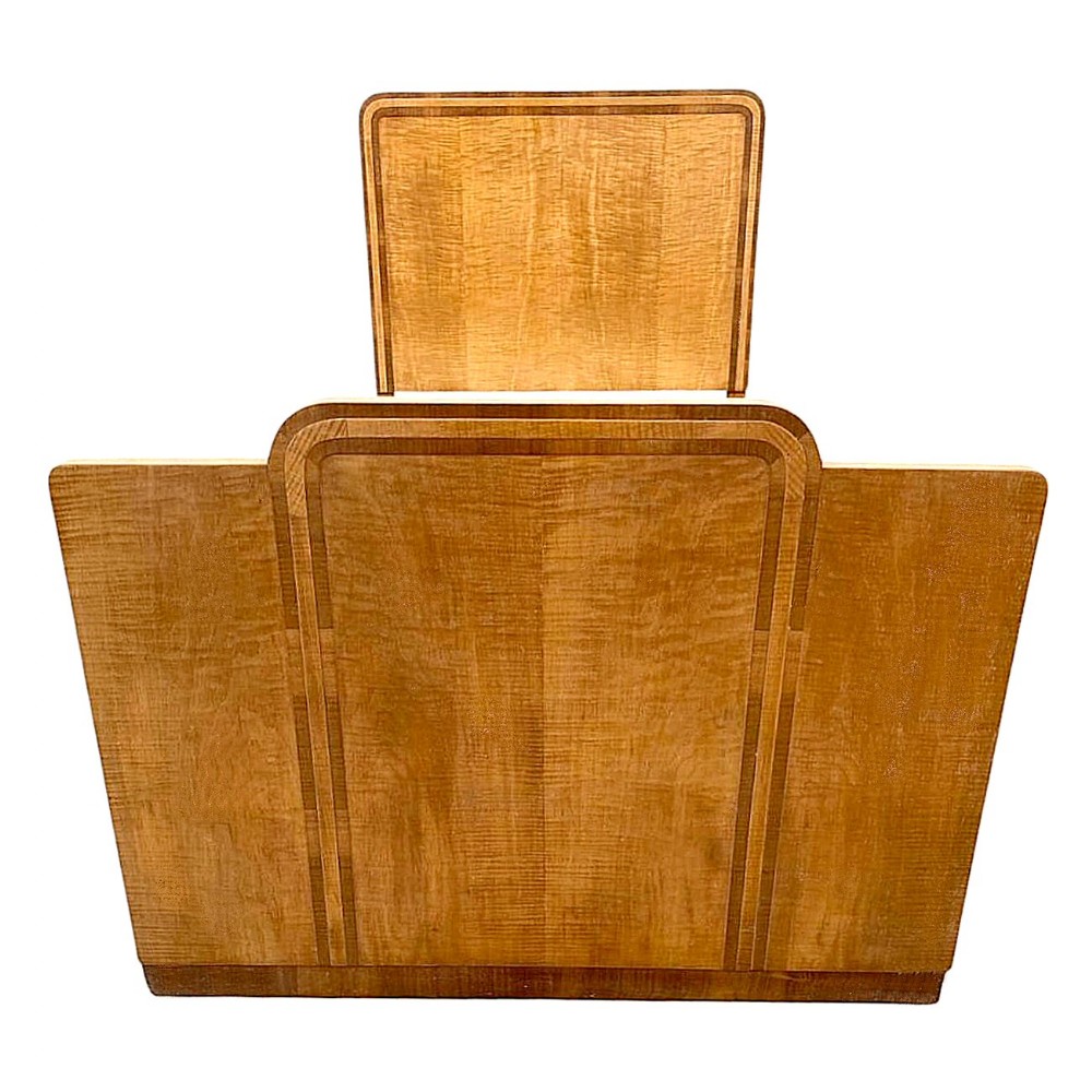 An Art Deco single bed frame featuring figured satinwood and blonde walnut veneers with rounded top corners and dark wood band inlay.