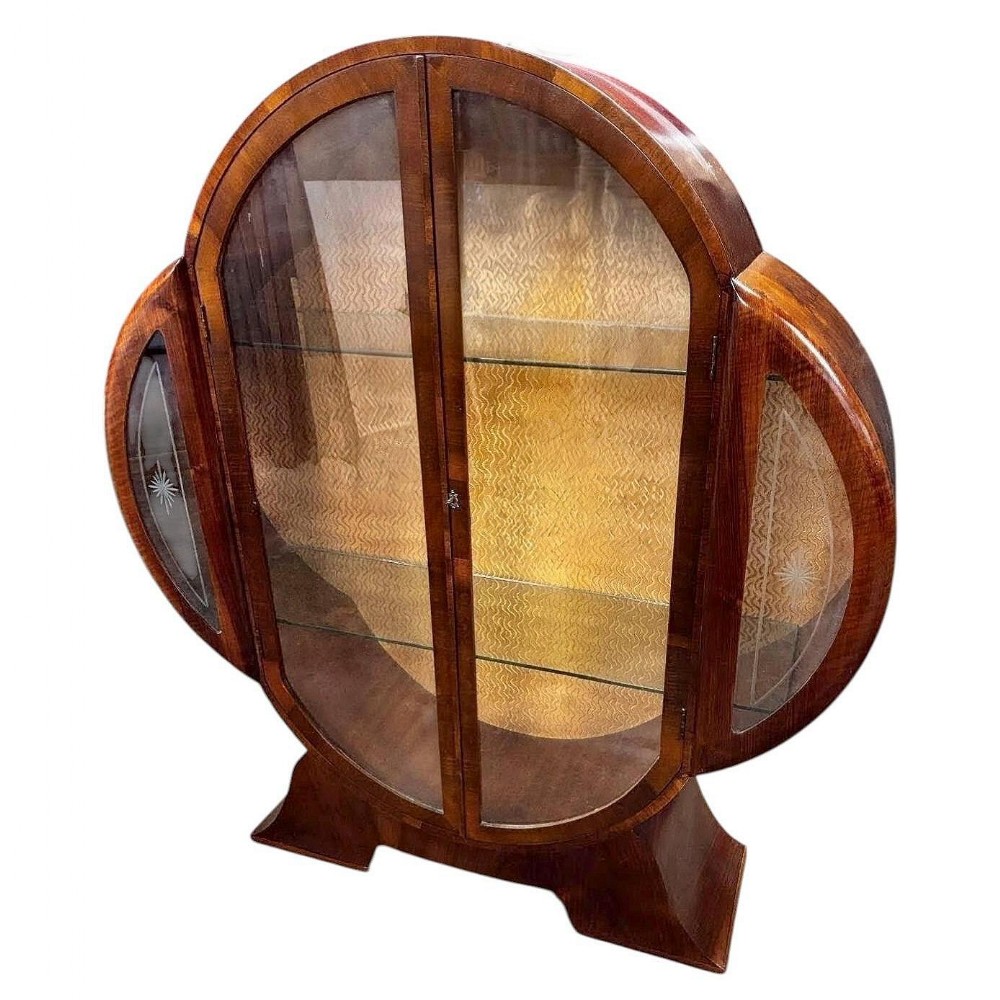 A 1930s Art Deco walnut display cabinet featuring a clove-shaped outline, two central glazed doors, etched glass side panels, and a patterned fabric interior.
