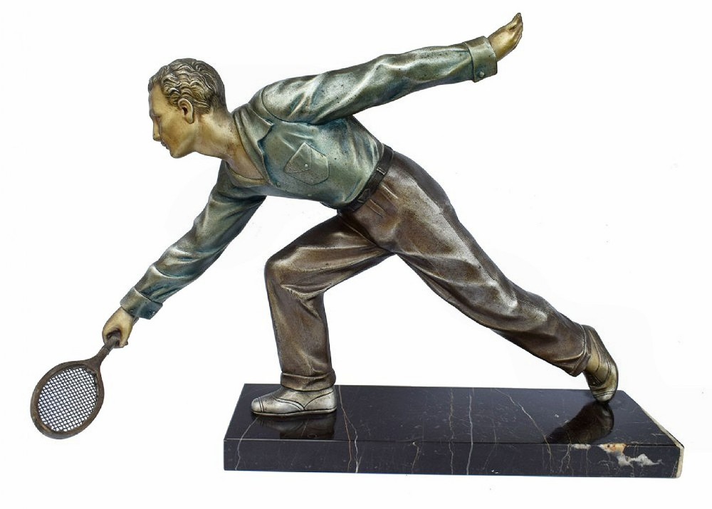 An Art Deco patinated metal sculpture of a male tennis player reaching low to hit a ball with a racket, mounted on a rectangular black marble base.
