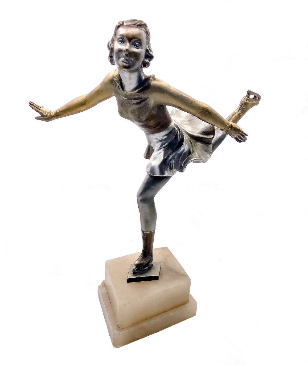 An Art Deco cold-painted spelter figure depicting a female ice skater mid-pose on a stepped square onyx plinth.