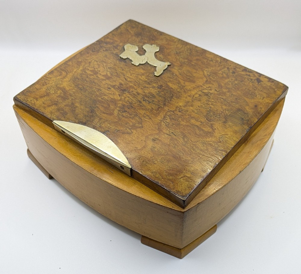 An Art Deco burr walnut cigarette box with a brass front latch and an inlaid metal Scottie dog motif on the lid. View II