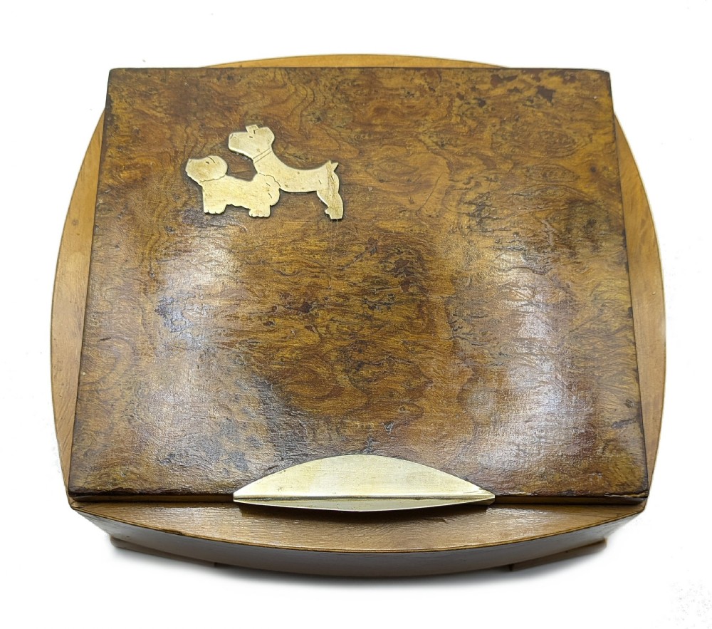 An Art Deco burr walnut cigarette box with a brass front latch and an inlaid metal Scottie dog motif on the lid. View VIII