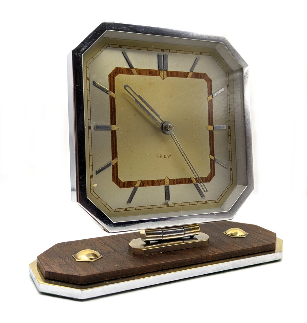 An Art Deco octagonal desk clock featuring a chrome frame, walnut accents, brass dial markers, and a stepped timber and metal plinth. View II
