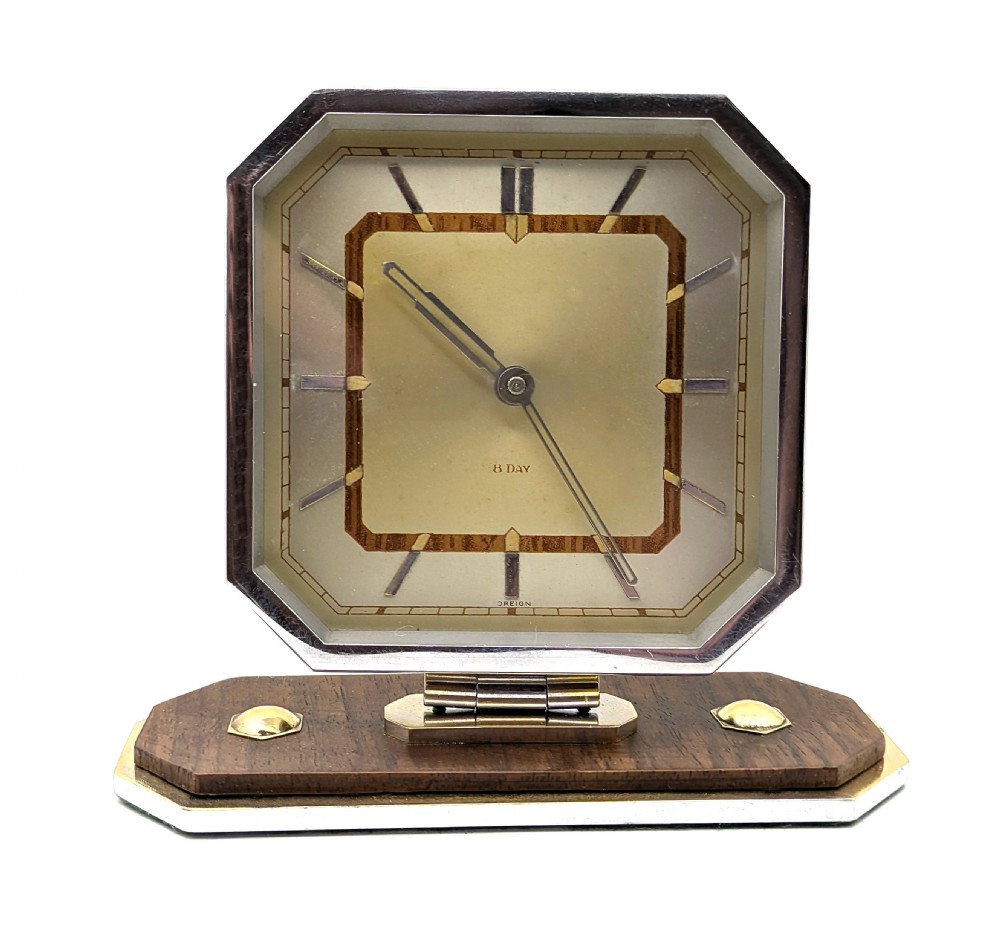 An Art Deco octagonal desk clock featuring a chrome frame, walnut accents, brass dial markers, and a stepped timber and metal plinth. View III