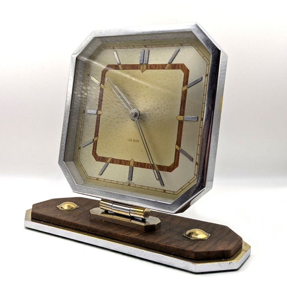 An Art Deco octagonal desk clock featuring a chrome frame, walnut accents, brass dial markers, and a stepped timber and metal plinth. View IV