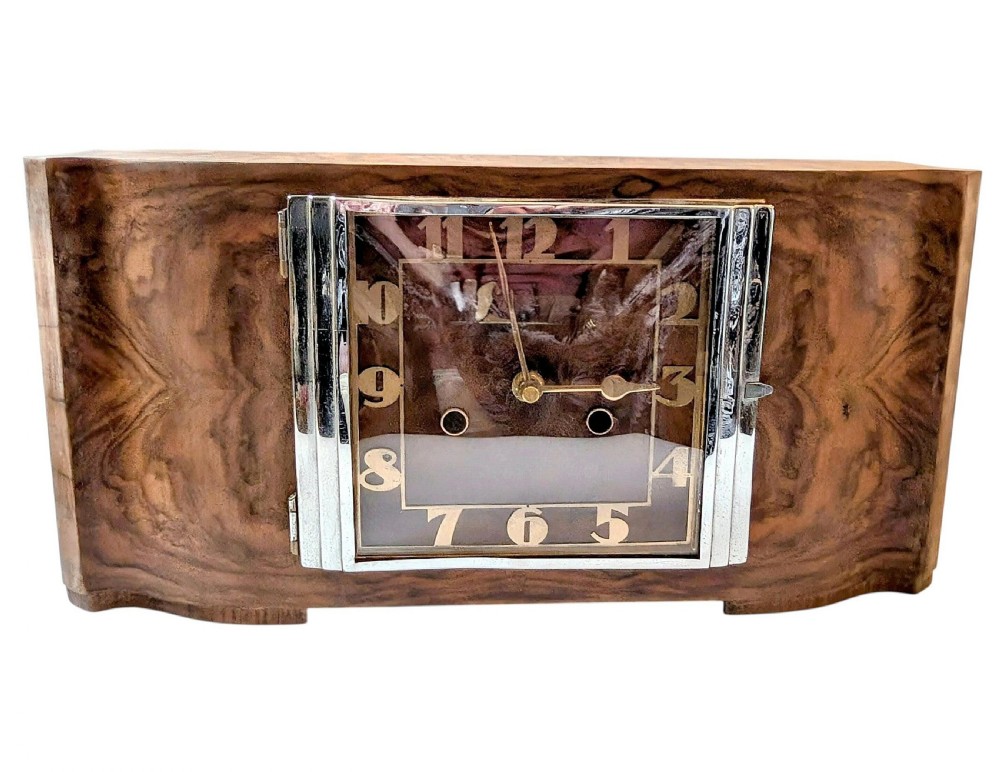 An Art Deco horizontal mantel clock crafted from figured walnut veneer featuring a square glass dial set within a polished chrome frame.