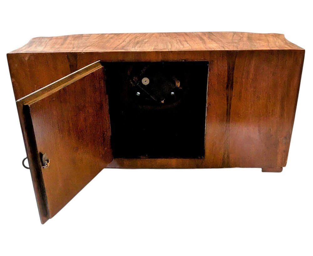 An Art Deco horizontal mantel clock crafted from figured walnut veneer featuring a square glass dial set within a polished chrome frame. View IX