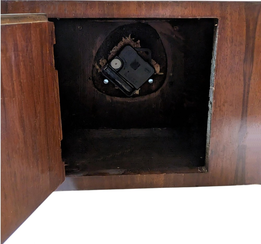 An Art Deco horizontal mantel clock crafted from figured walnut veneer featuring a square glass dial set within a polished chrome frame. View X