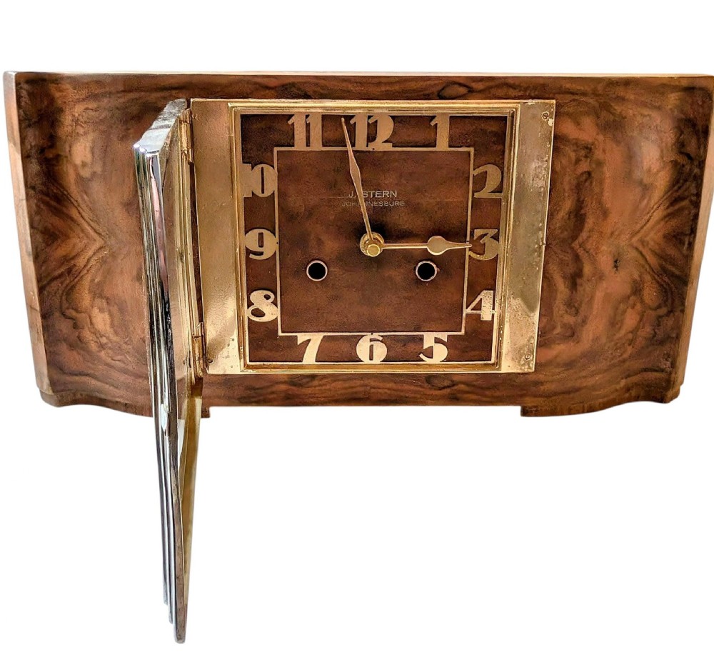 An Art Deco horizontal mantel clock crafted from figured walnut veneer featuring a square glass dial set within a polished chrome frame. View XII