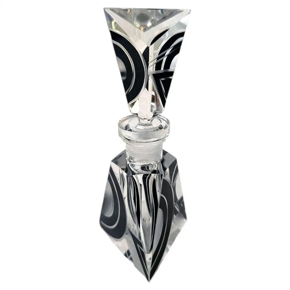 A clear geometric cut glass perfume bottle featuring bold black enamel abstract patterns and a matching angular glass stopper.