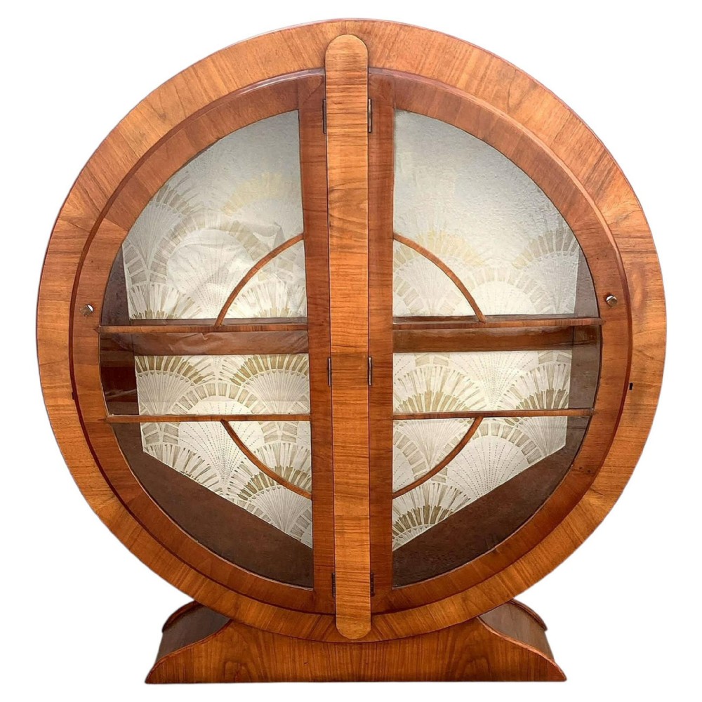 A circular Art Deco display cabinet made from warm brown walnut with glass doors and internal shelving.