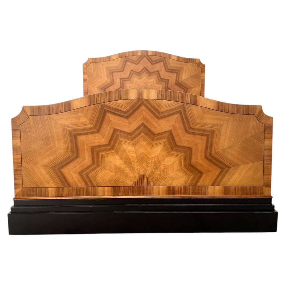 An Art Deco walnut double bedstead featuring a sunburst geometric veneer pattern on the headboard and footboard above an ebonised base. View II