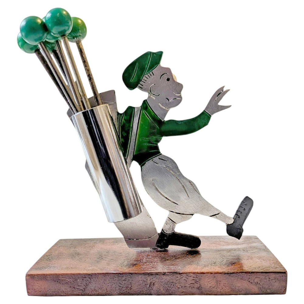 An Art Deco metal cocktail pick set shaped as a stylised golfer figure wearing a green cap and top, mounted on a rectangular brown base holding green-topped picks.