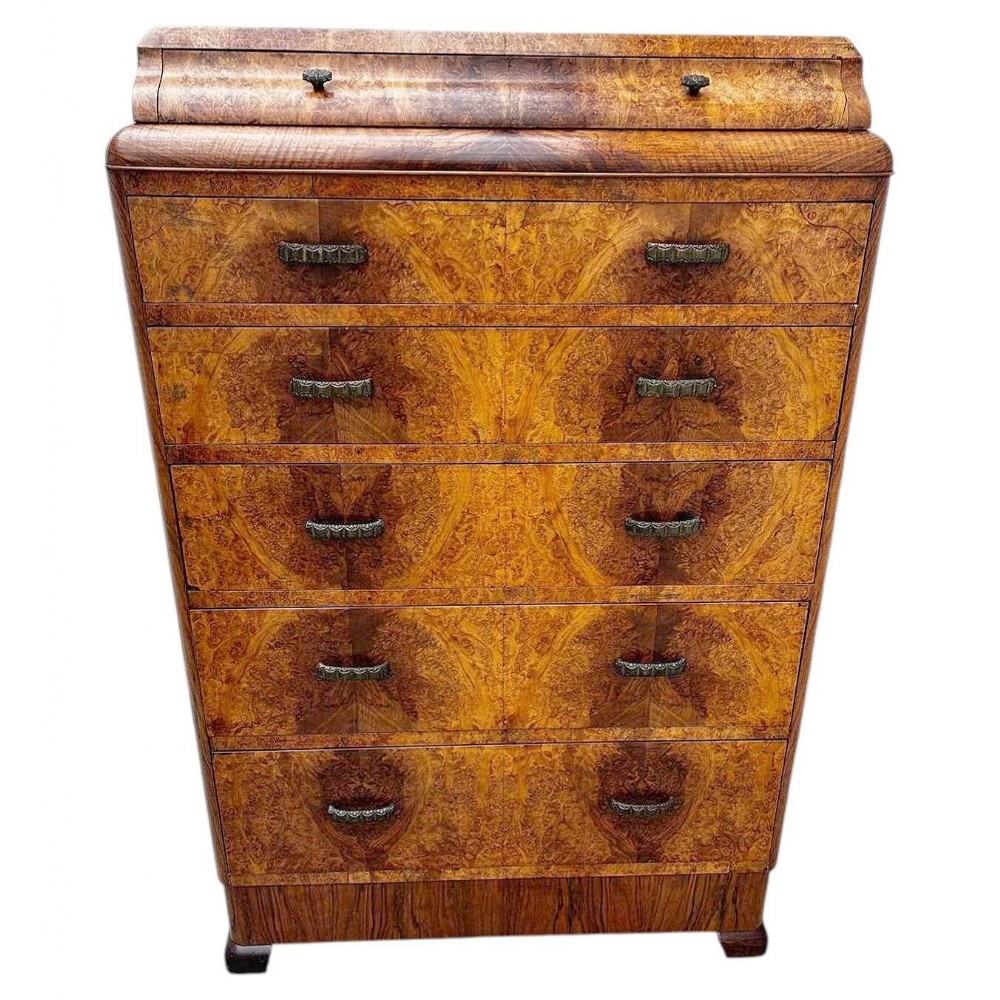 An English Art Deco burr walnut chest of six drawers featuring stylized handles and a stepped top section.