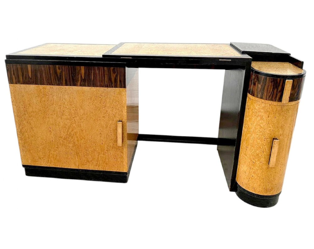 An Art Deco writing desk featuring blonde birdseye maple veneer, dark macassar ebony accents, and asymmetrical pedestal storage.