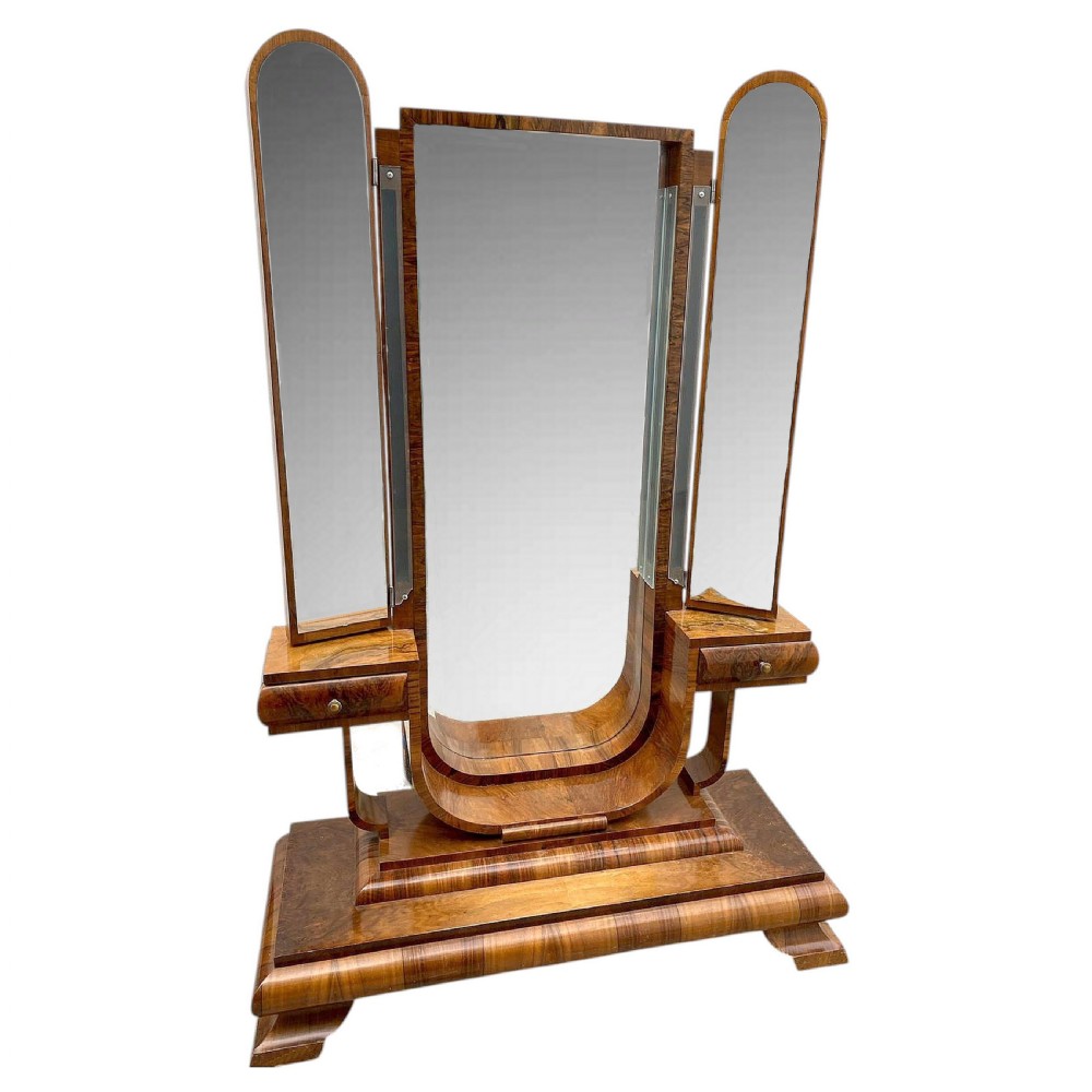 An Art Deco figured walnut freestanding tri-fold cheval dressing mirror with side drawers and stepped plinth base.