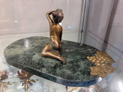 fig 1. An Art Nouveau bronze figure of a seated woman leaning back on a green marble surface.