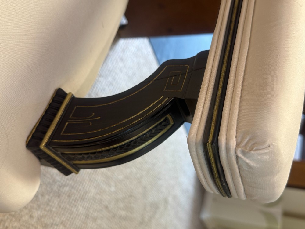 An Aesthetic Movement ebonised wooden settee featuring gilt incised line decorations and cream upholstery on the seat and backrest. View VI