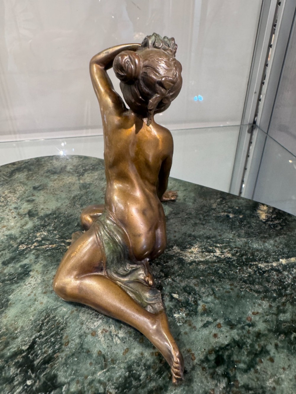 An Art Nouveau bronze figure of a seated woman leaning back on a green marble surface. View V