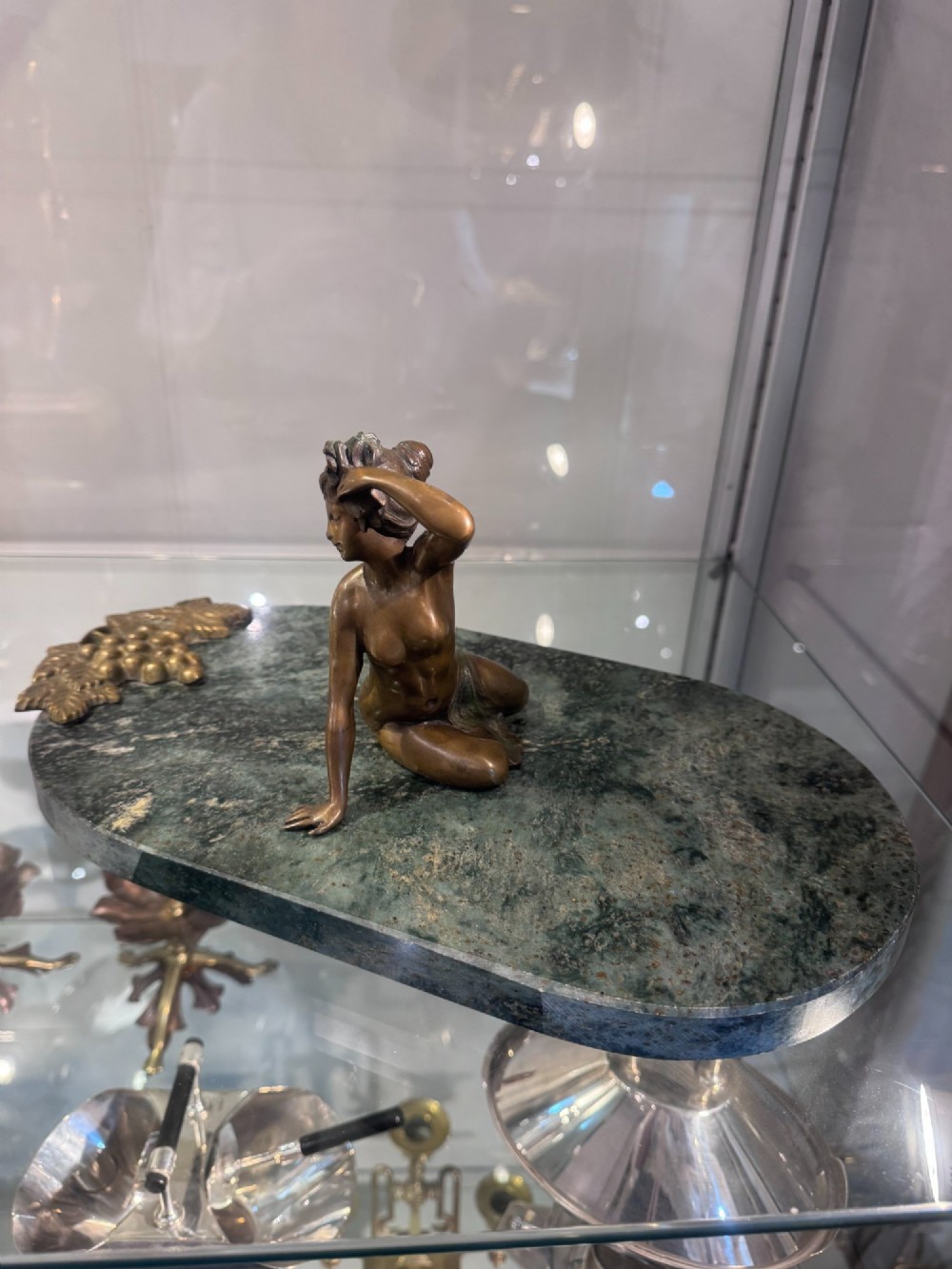 An Art Nouveau bronze figure of a seated woman leaning back on a green marble surface. View VI