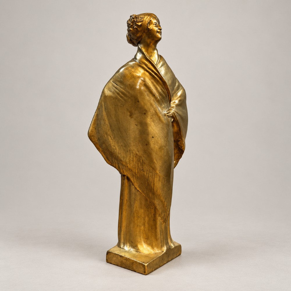 An Art Nouveau gilded bronze sculpture depicting a woman draped in a heavy fringed shawl looking upward, mounted on a square integrated base.