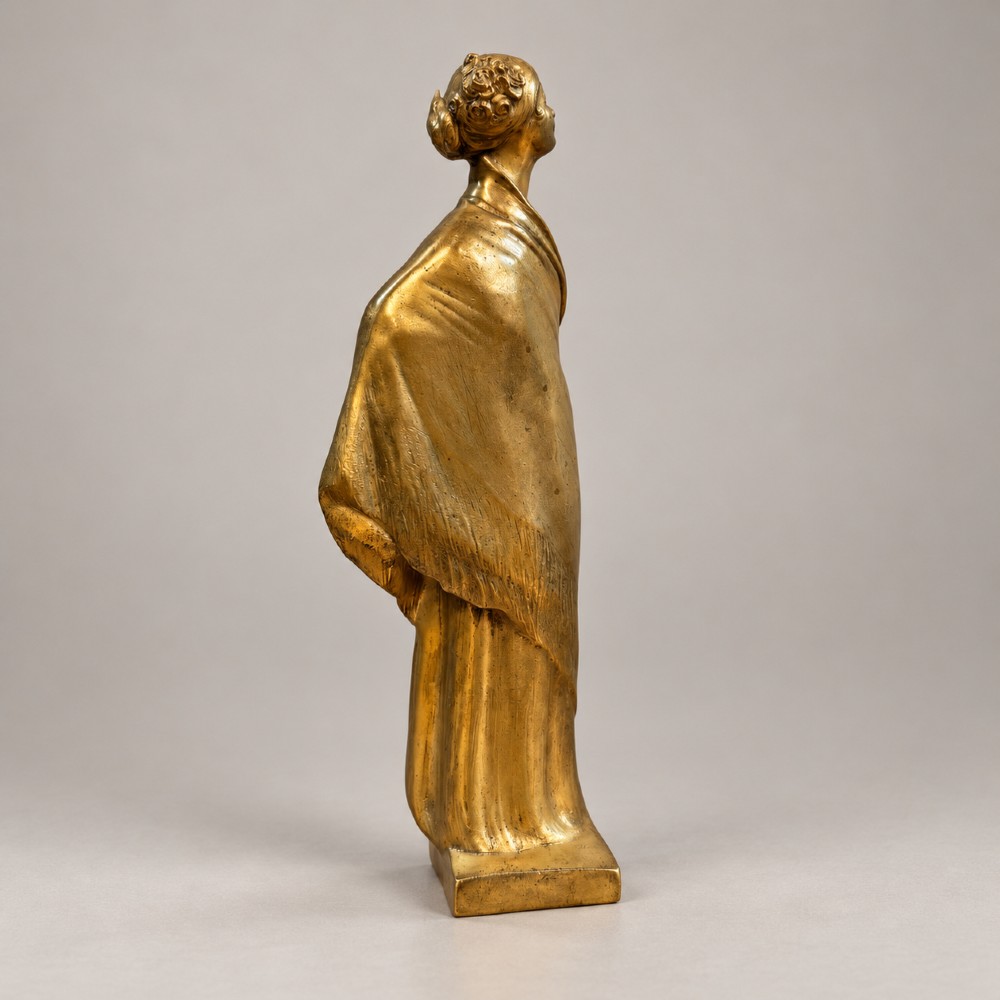 An Art Nouveau gilded bronze sculpture depicting a woman draped in a heavy fringed shawl looking upward, mounted on a square integrated base. View V